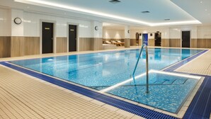 Una amplia piscina interior con agua cristalina y paredes y suelo de baldosas.