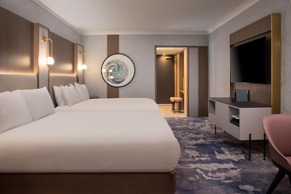 Ein Hotelzimmer mit einem großen Bett, einem Schreibtisch, einem Fernseher und einem gerahmten Kunstwerk an der Wand.