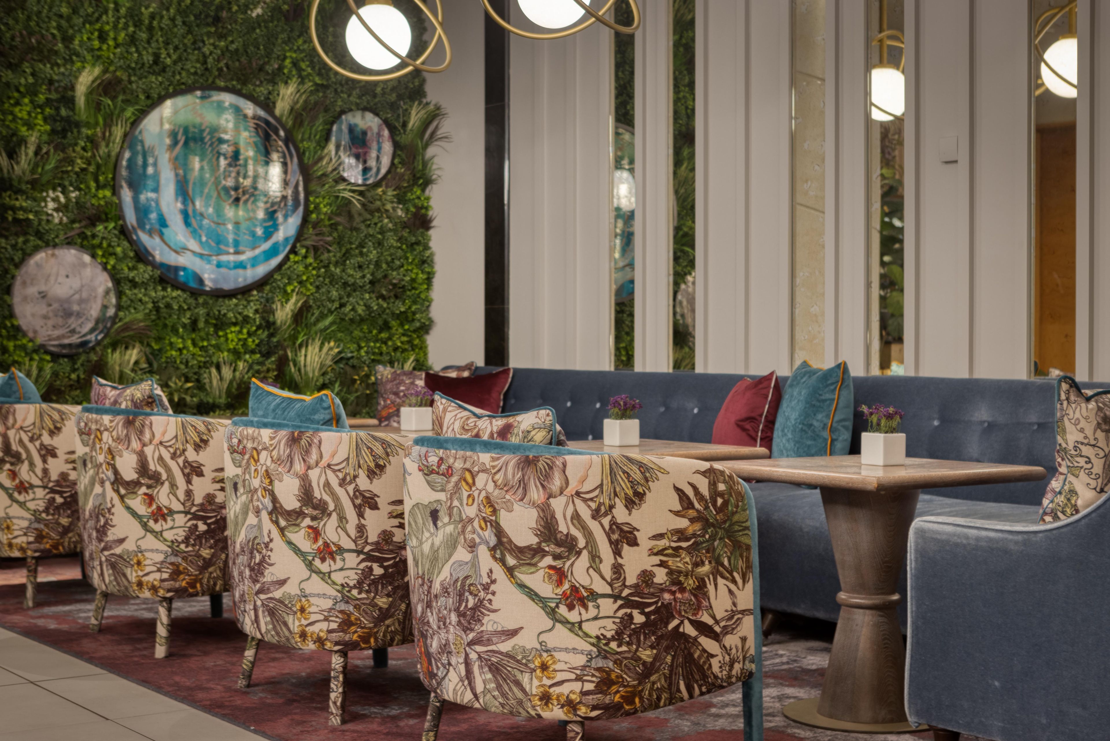 A seating area with floral upholstery, a blue sofa, and a round table.