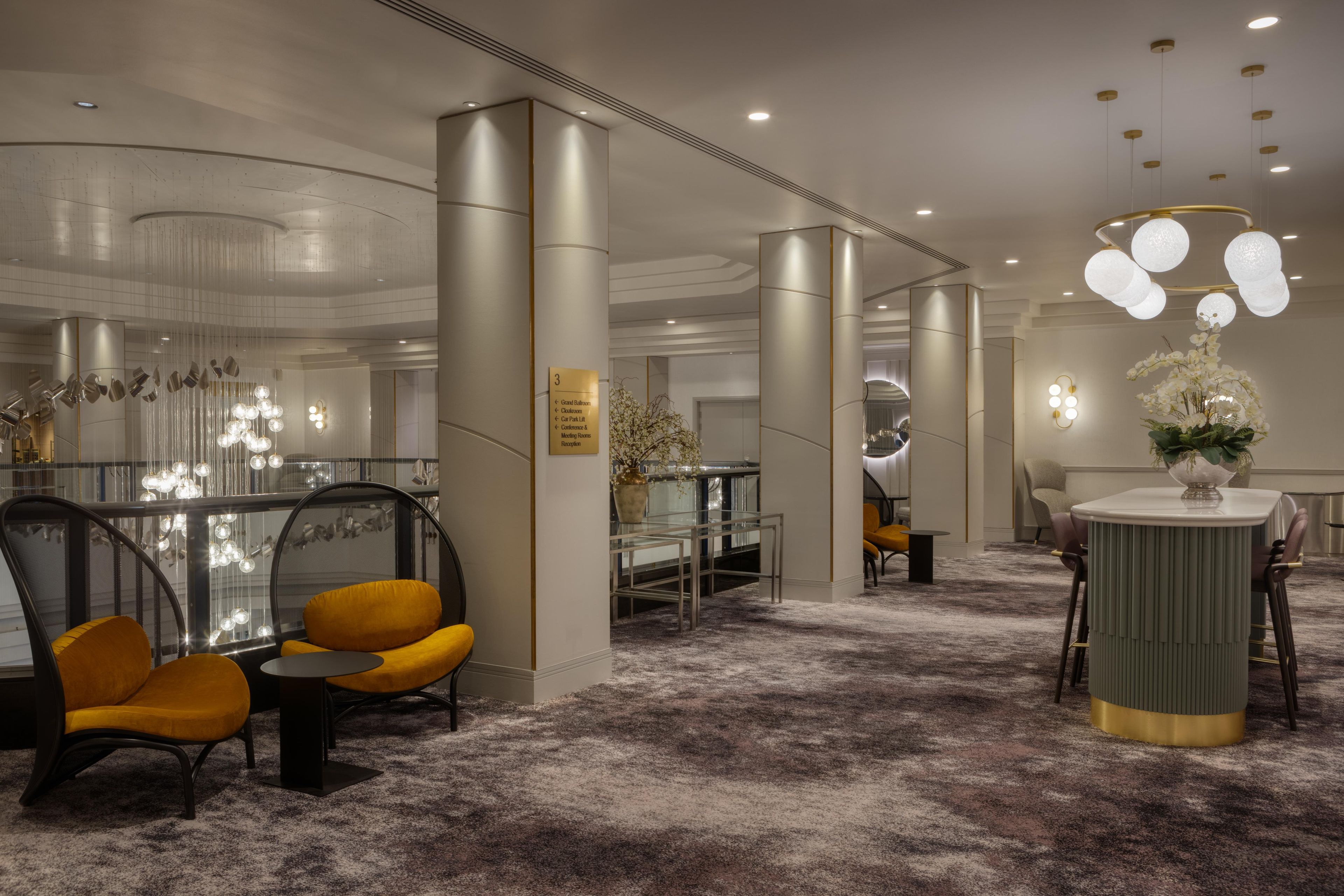 Un moderno vestíbulo de hotel con mostrador de recepción, zona de estar y una escalera.