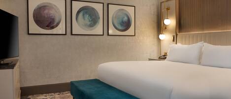 Une chambre d’hôtel avec un grand lit, un banc, une télévision et trois tableaux accrochés au mur.