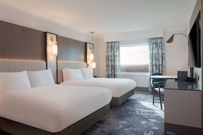 Two spacious beds with crisp linens, a desk for work, and a window with a view.