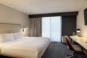 A hotel room with a large bed, a desk, a chair, and a window with curtains. - Courtyard by Marriott Atlanta Northlake (Tucker)