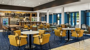 Eine moderne Hotelhalle mit Barbereich, Sitzgelegenheiten und Blick ins Freie.