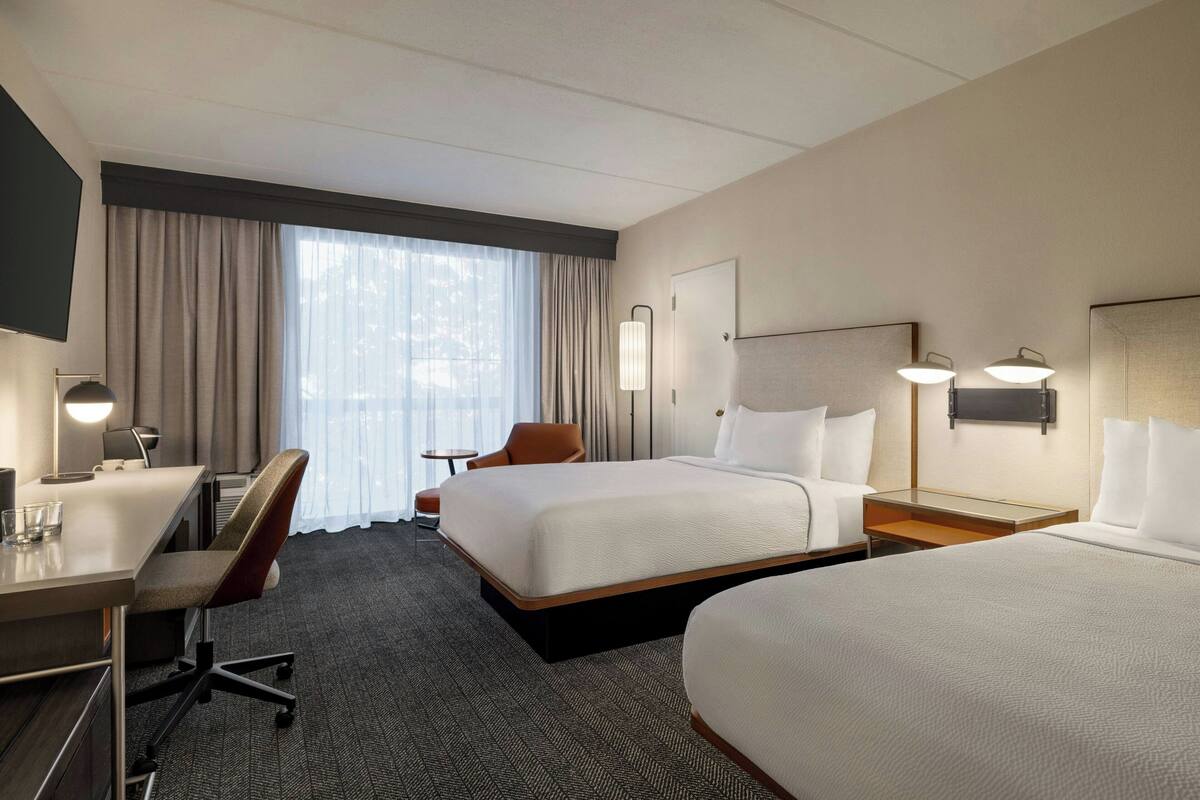 Una habitación de hotel con cama, escritorio, silla y televisión.