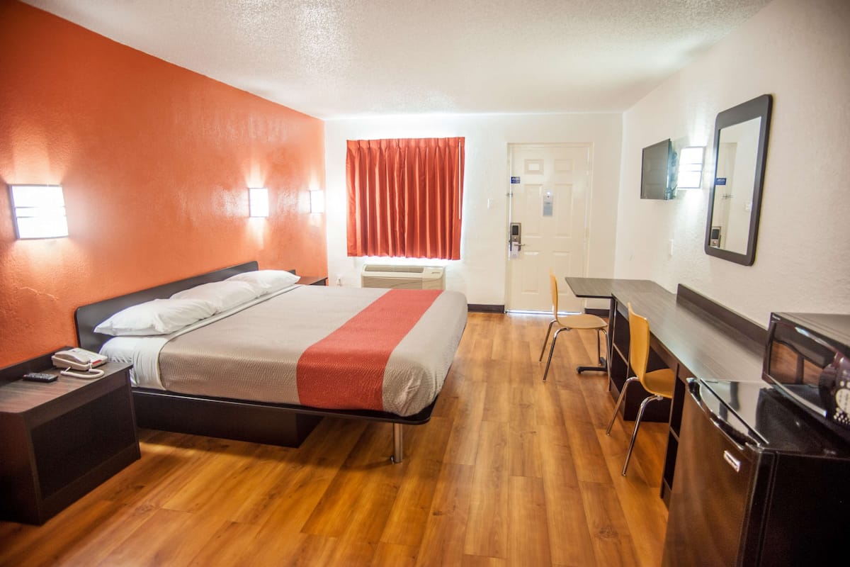 Une chambre d’hôtel comprenant un lit, une table de chevet, un bureau, une chaise et un téléviseur.