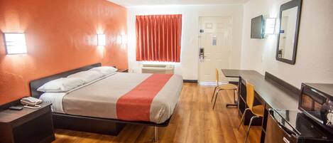 Une chambre d’hôtel comprenant un lit, une table de chevet, un bureau, une chaise et un téléviseur.