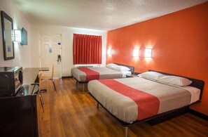 Two single beds with red and white bedding, a desk, and a flat-screen TV.