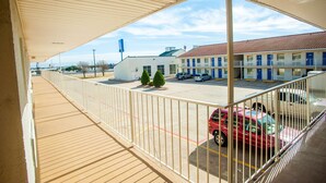 Un hotel con balcón cubierto, estacionamiento y un edificio con puertas azules.