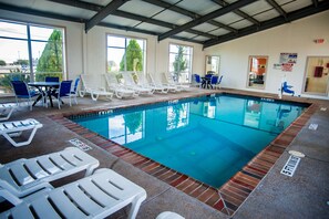 An indoor swimming pool with lounge chairs and tables, clear poolside area, and a covered roof structure. - Motel 6 Corsicana, TX (Corsicana)