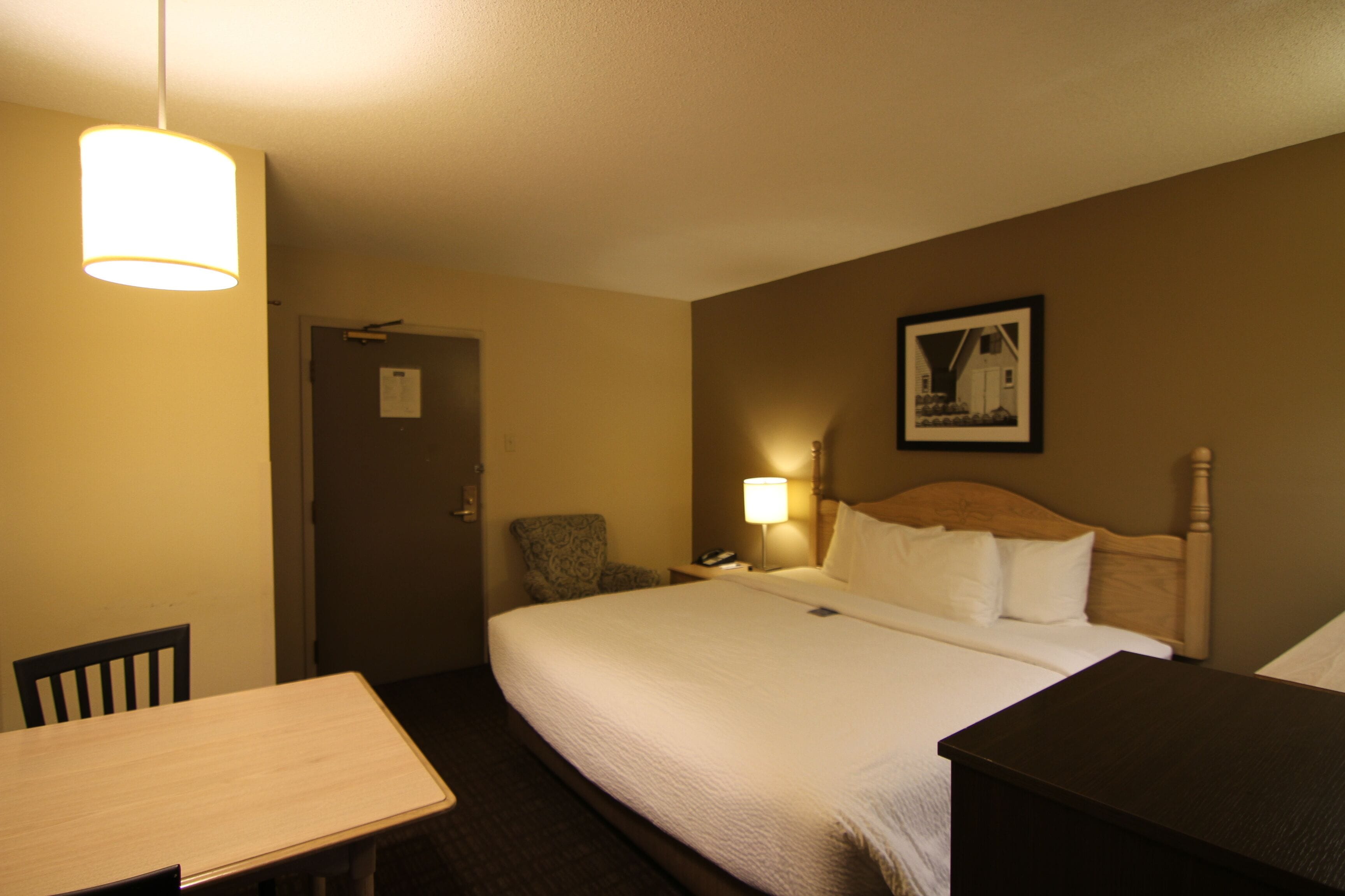 Una habitación de hotel con una cama grande, un escritorio, una silla y una lámpara.