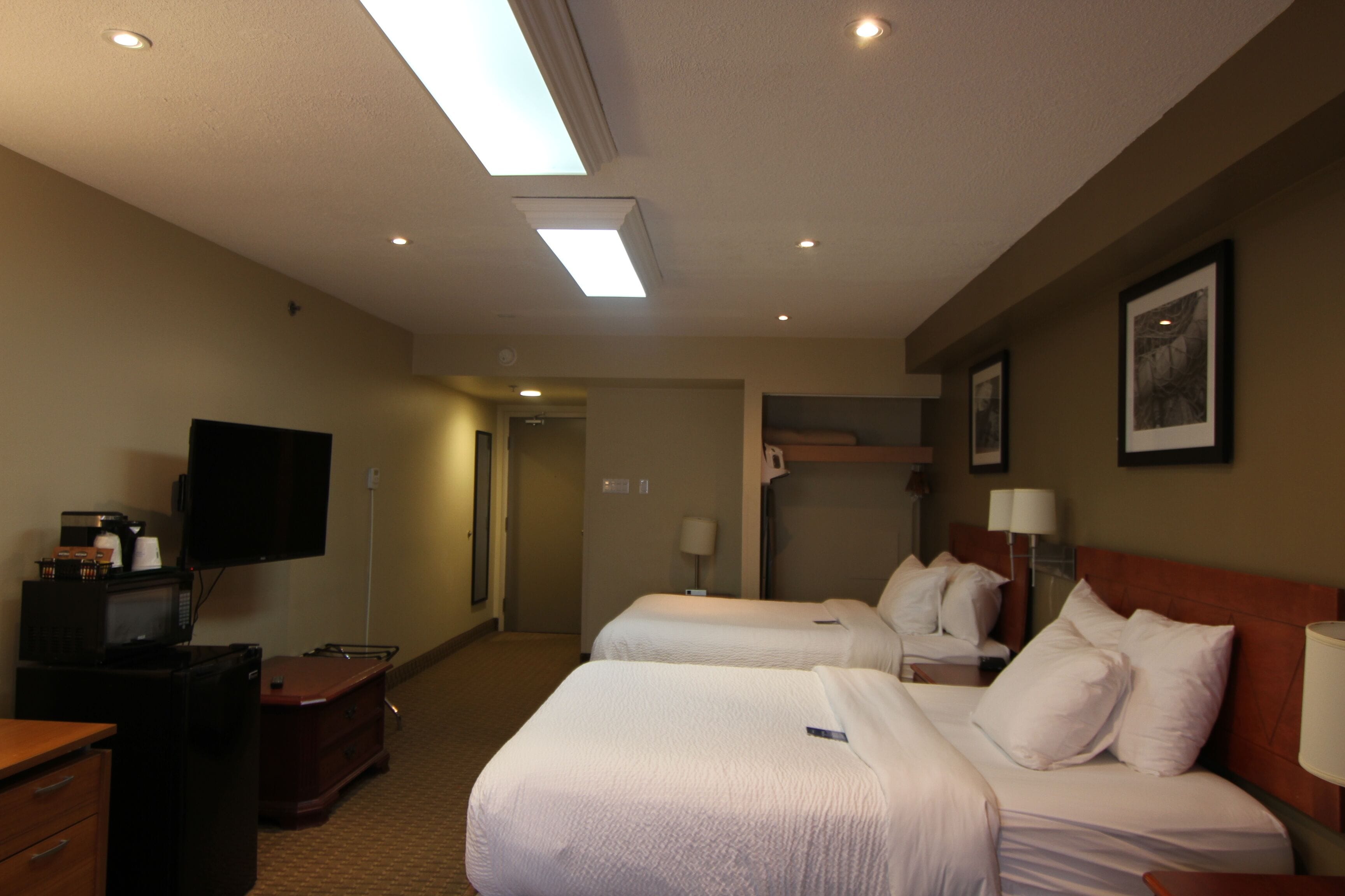 Habitación de hotel con dos camas, televisión, escritorio con computadora y microondas.