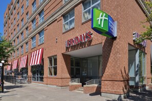 A brick building with a storefront labeled 'FRIDAYS' and a green sign with a white 'H' indicating a Holiday Inn Express & Suites.