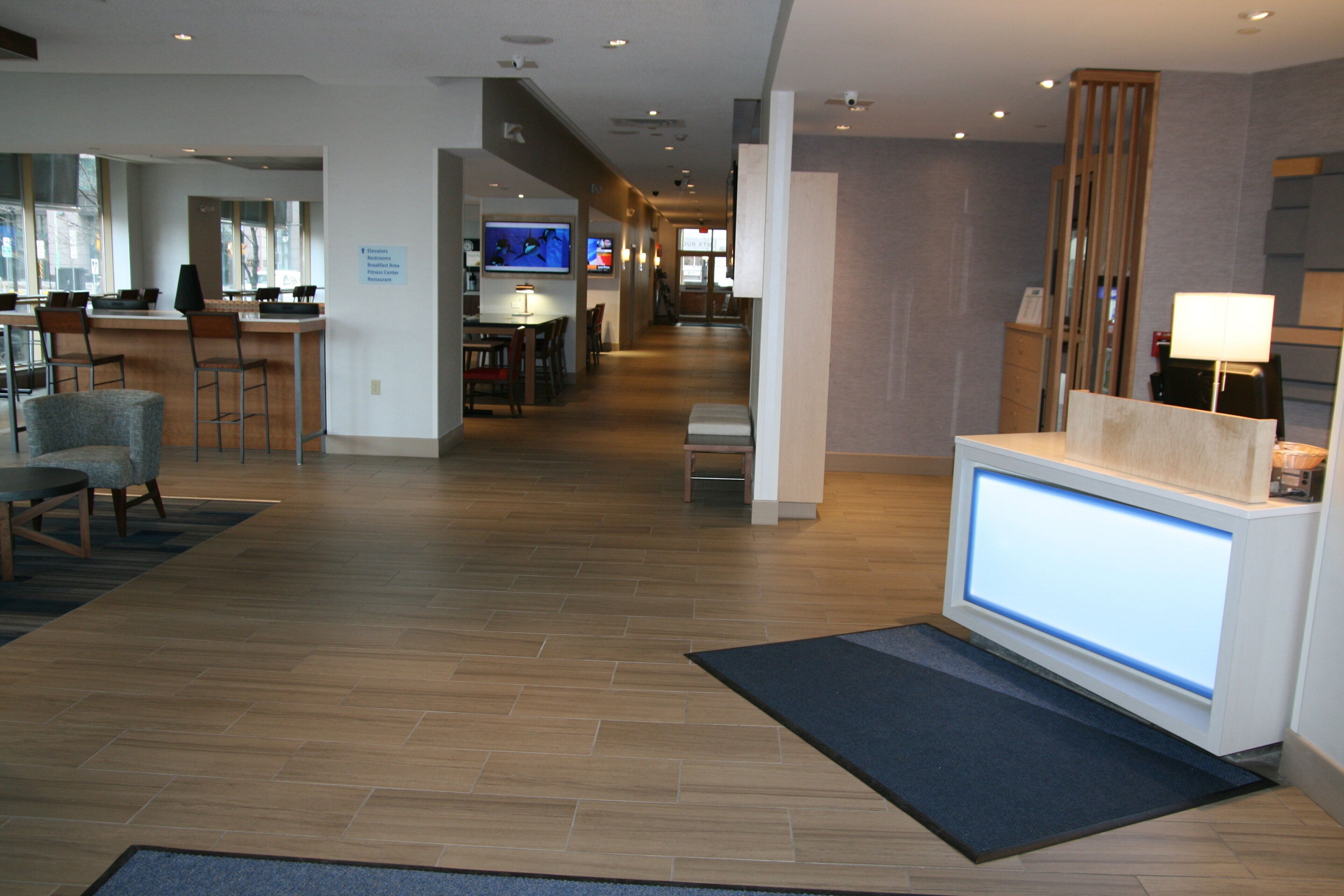 A hotel lobby with a reception desk, seating area, and a bar.