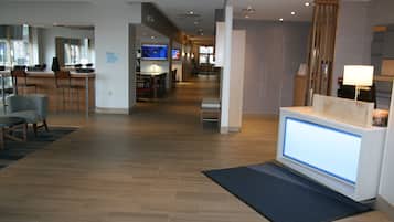 A hotel lobby with a reception desk, seating area, and a bar.
