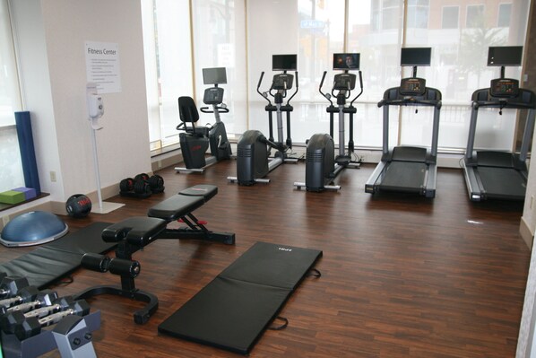 A fitness center with various exercise equipment including treadmills, elliptical machines, and free weights.