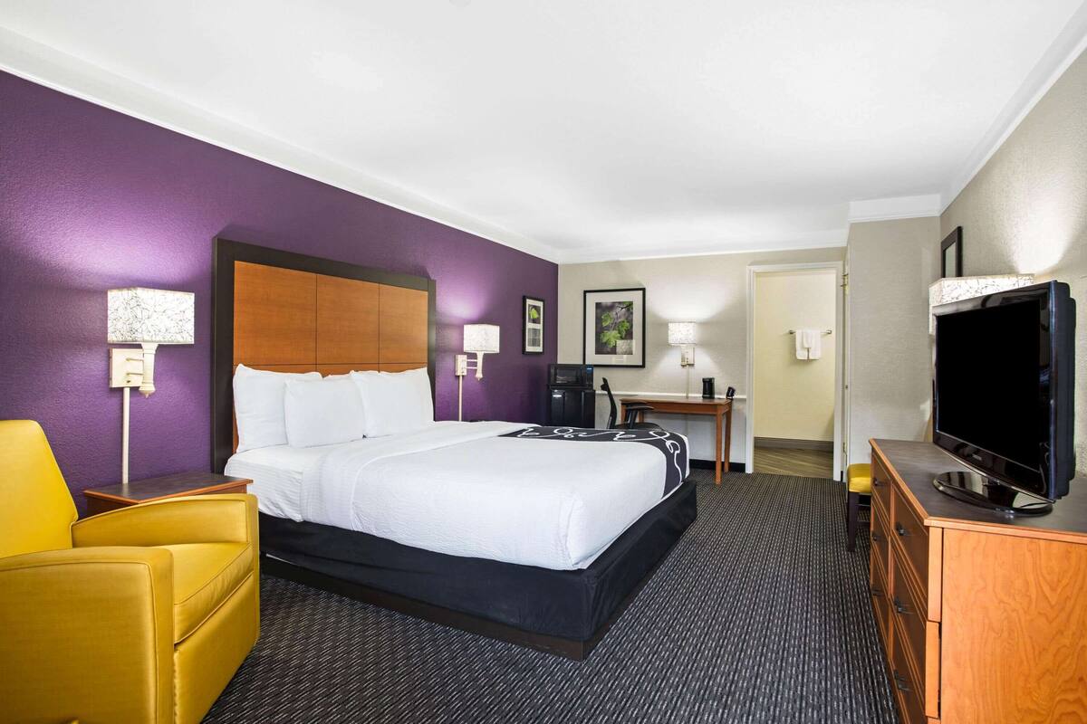 A hotel room with a bed, a desk, a television, and a chair.