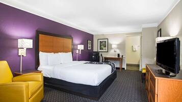 Une chambre d’hôtel avec un lit, un bureau, une télévision et une chaise.