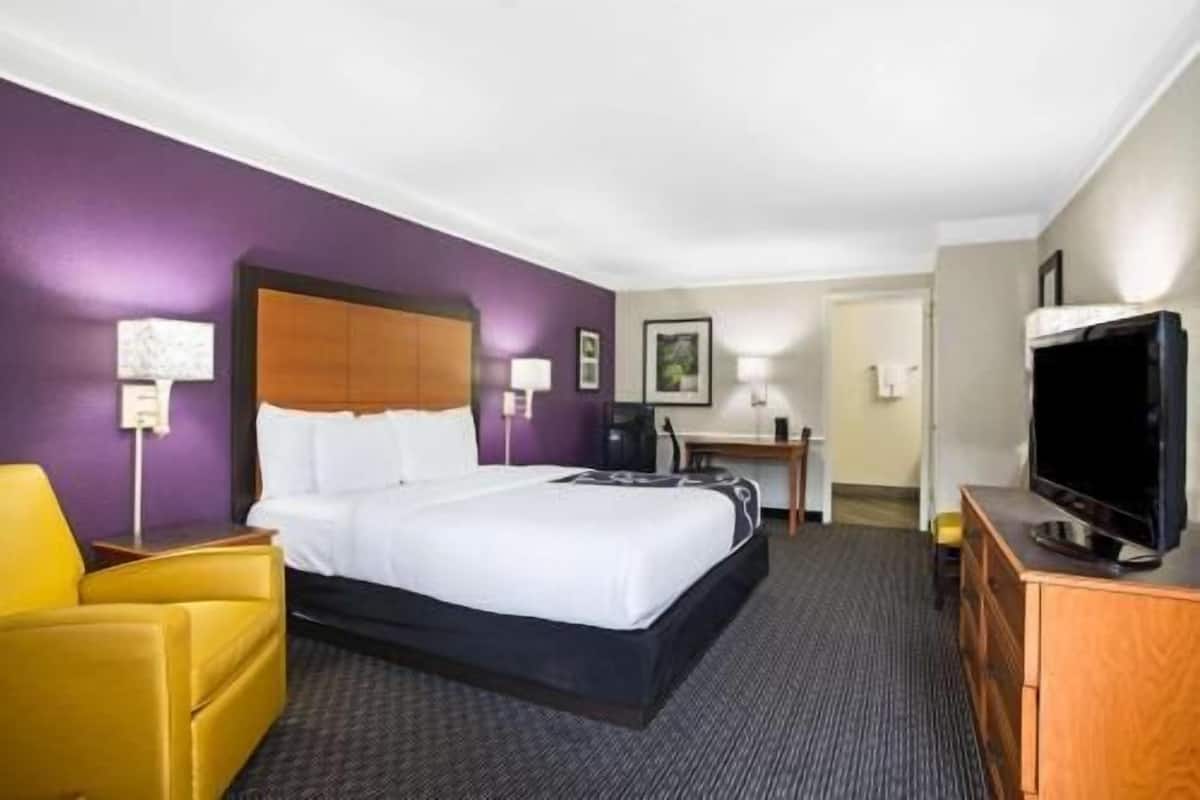 A hotel room with a bed, a desk, a chair, a television, and a bathroom.