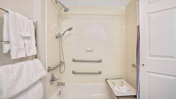 A bathroom with a bathtub, a shower, and a towel rack with multiple towels.