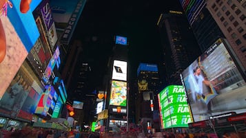 Una calle urbana concurrida de noche, con vallas publicitarias e iluminación brillante.