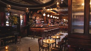 A bar with multiple stools and tables, a bar counter with bottles, and a decorative sign.