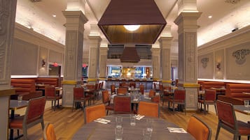 A spacious restaurant with high ceilings, ornate columns, and a central bar area.