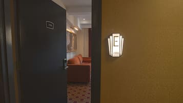 A hotel room with a door labeled '2102,' a patterned wall, and a light fixture with the number '2102' on it.