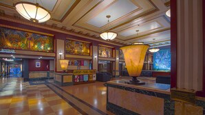 A lobby with a checkered floor, a reception desk, a large mural, and a gift shop.