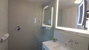 Une salle de bain moderne avec une douche à parois de verre, un lavabo en marbre et un grand miroir.