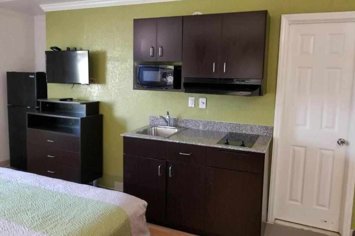 A compact kitchen with dark cabinets, a microwave, and a sink.