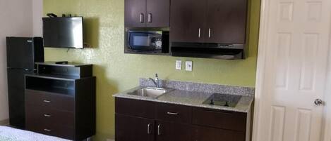 A compact kitchen with dark cabinets, a microwave, and a sink.