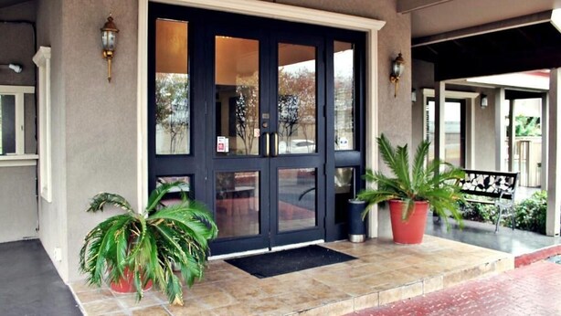 A building entrance with a dark-colored door, potted plants, and a bench. - The Inn at Market Square (San Antonio)