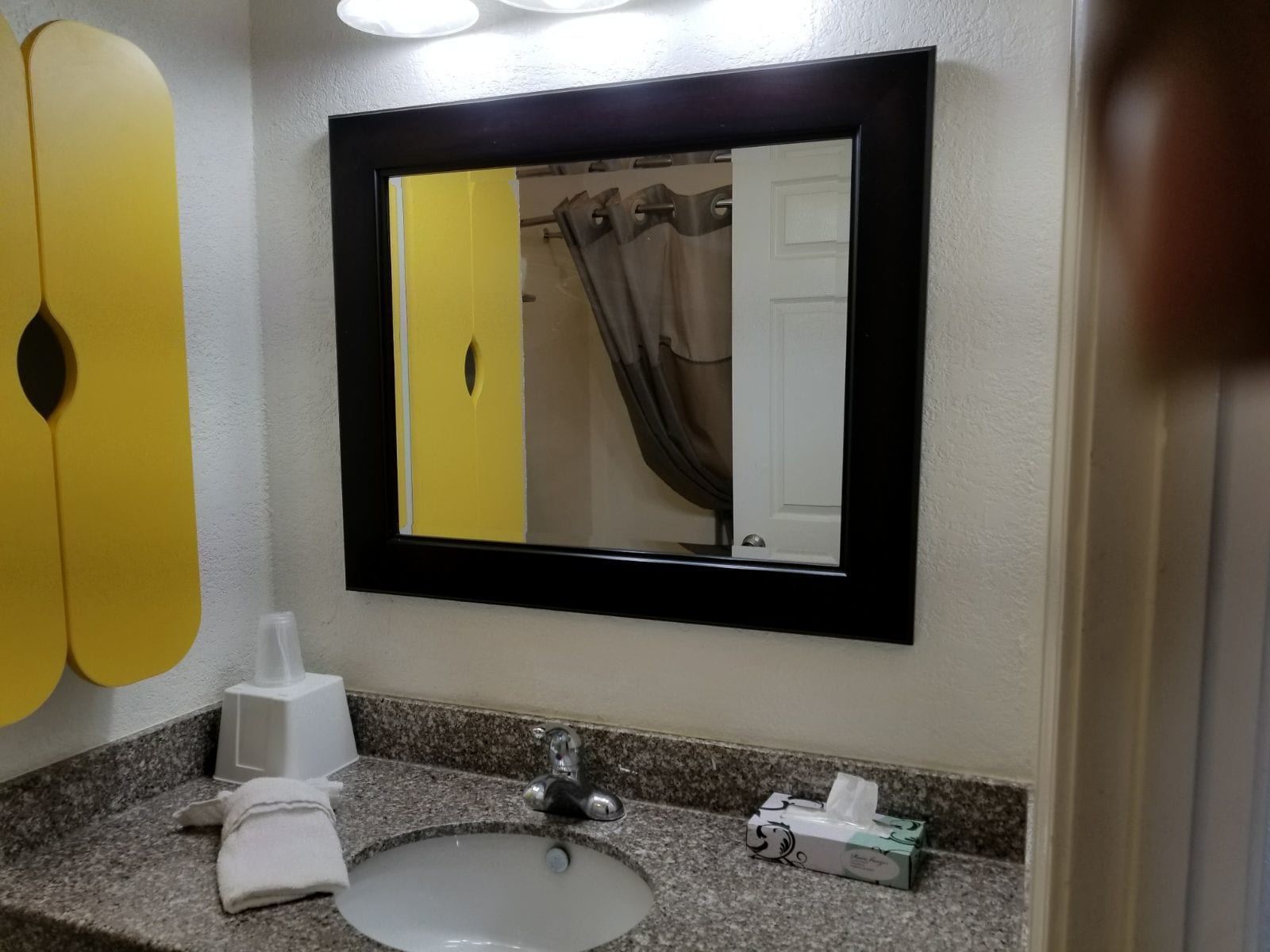 Un baño con lavabo, espejo y dispensador de toallas.