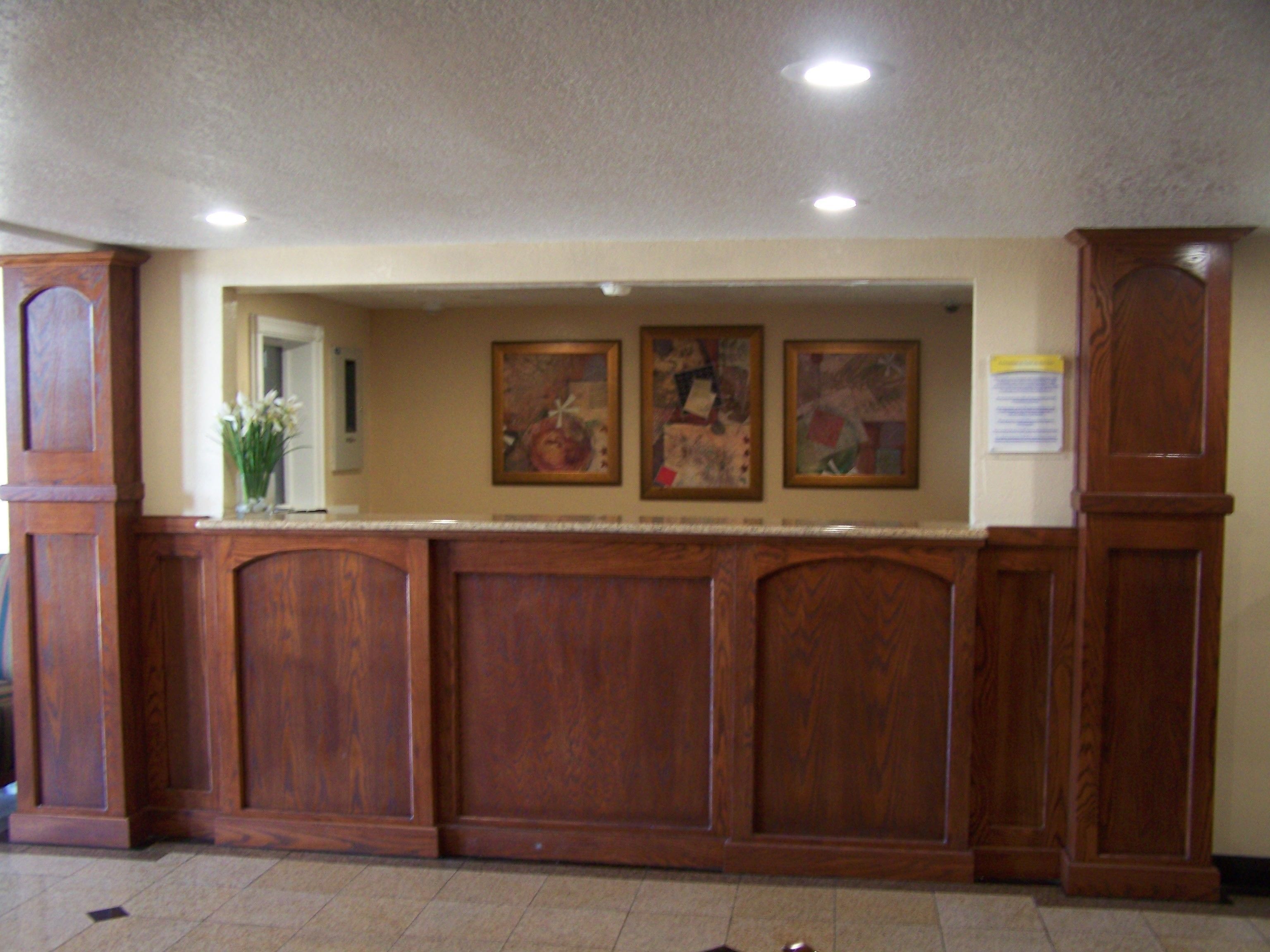 A reception area with a wooden reception desk, framed artwork on the wall, and a bulletin board.