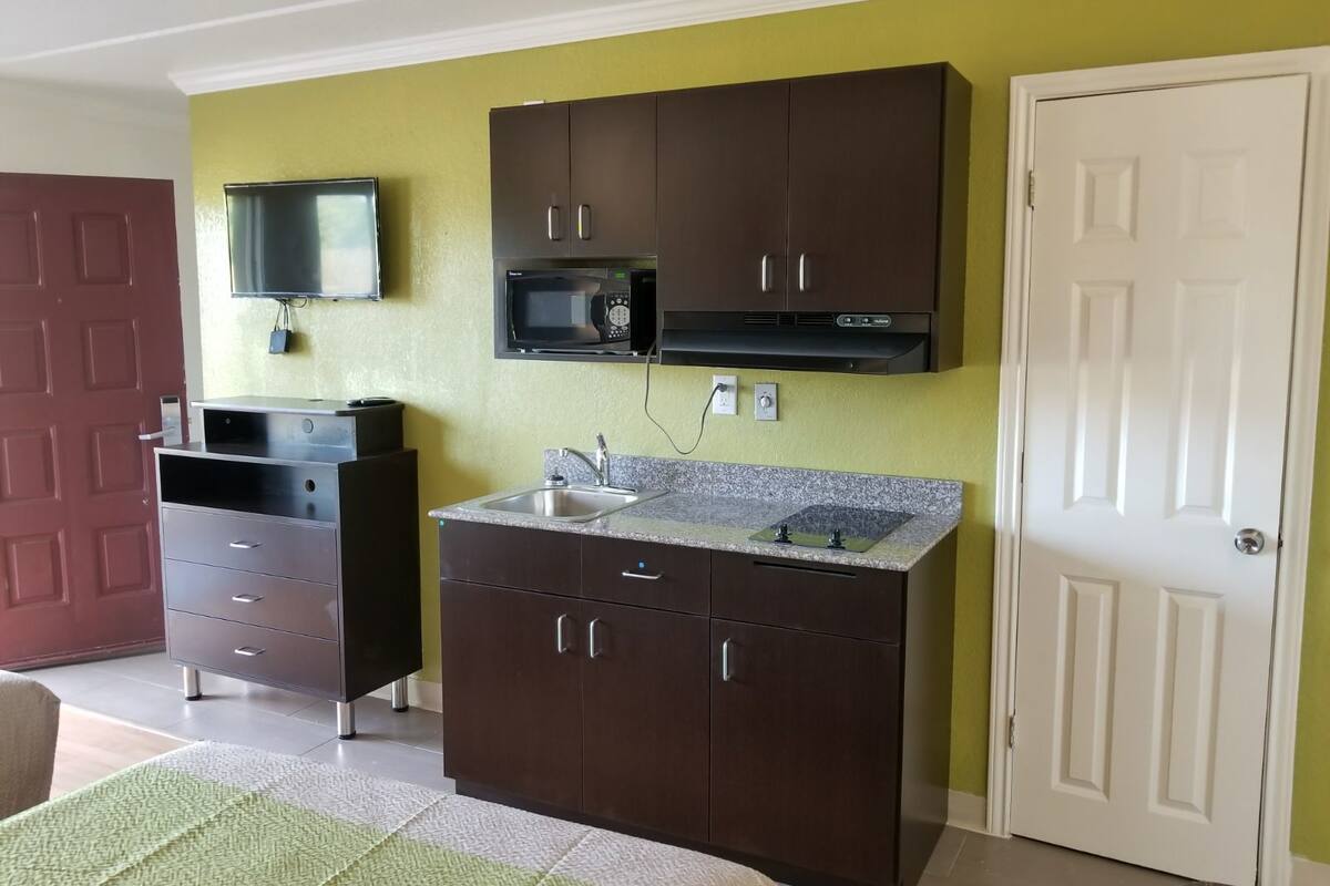 A compact kitchen with dark cabinets, a microwave, and a sink.