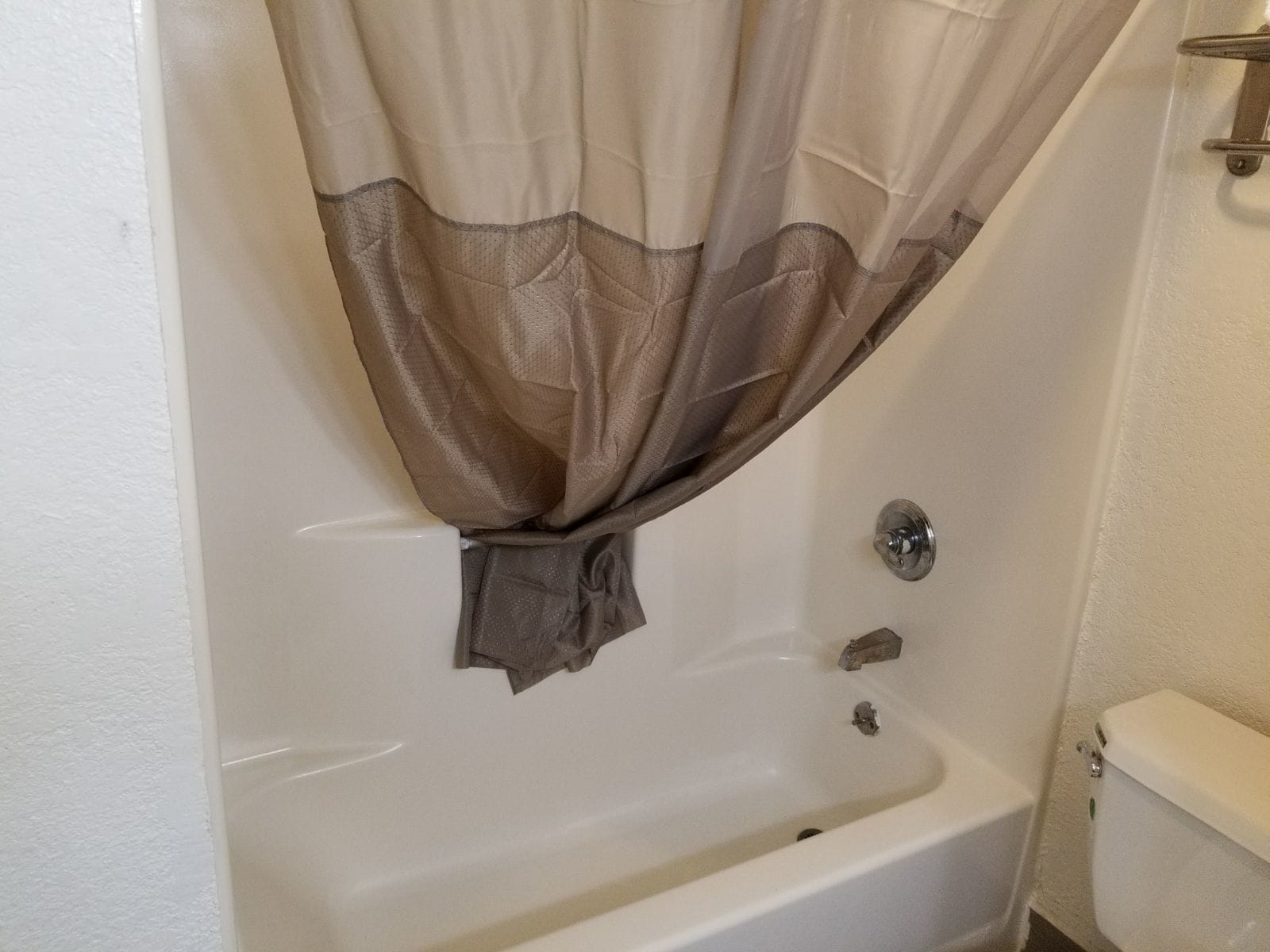 A bathroom with a bathtub, toilet, and a shower curtain.