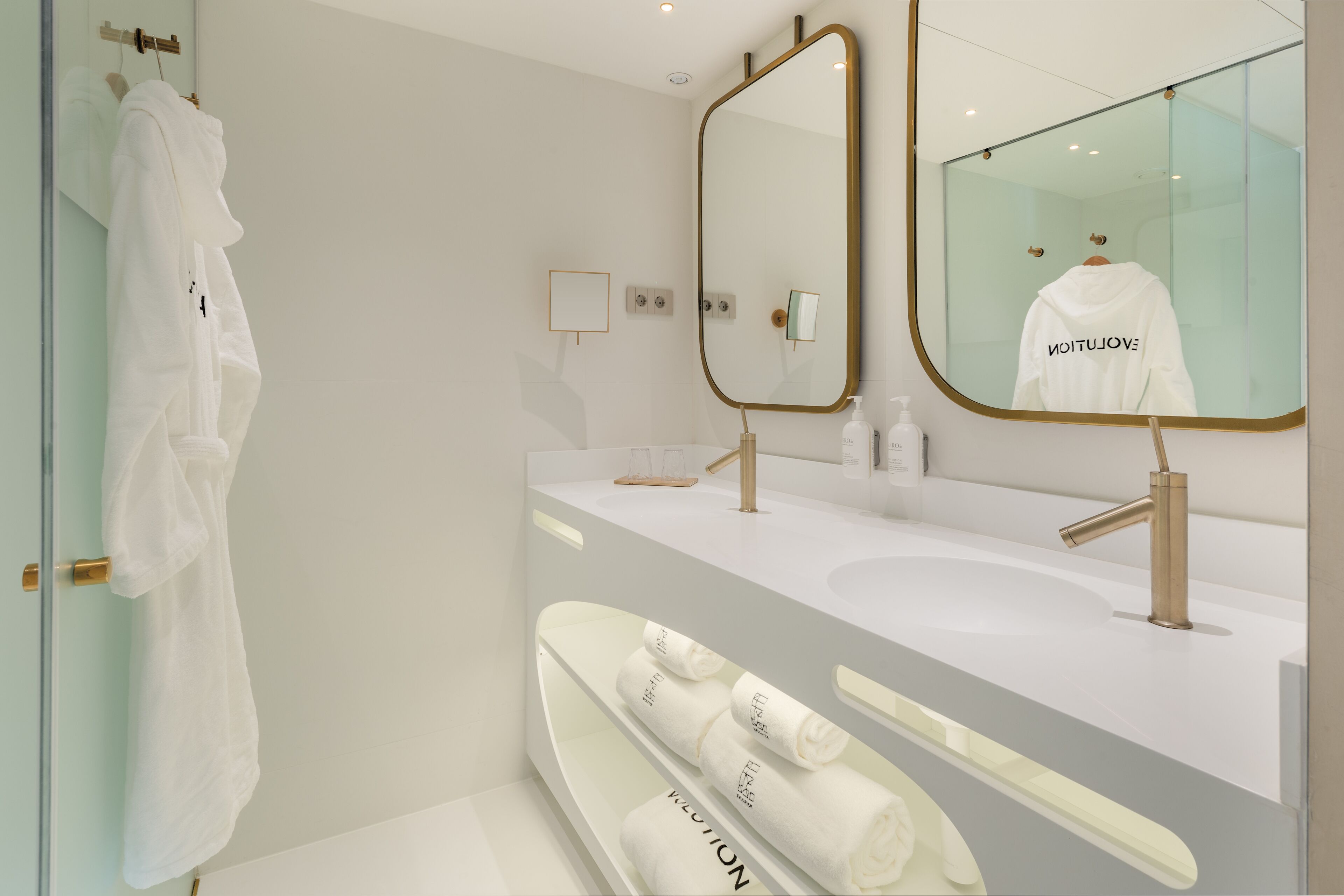 A modern bathroom with a large mirror, a white sink, and a towel rack.