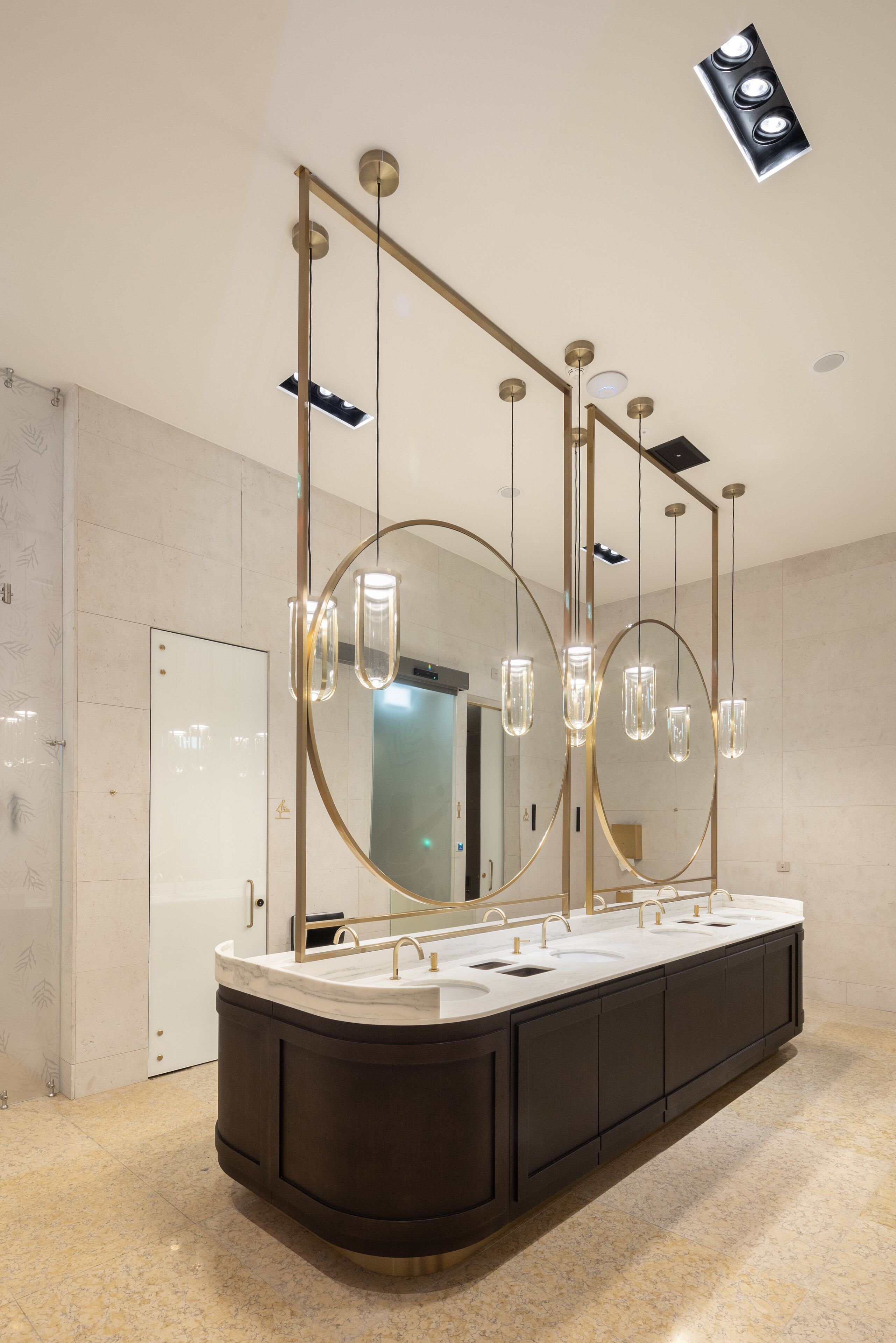 A modern bathroom with a large vanity, multiple mirrors, and pendant lighting.