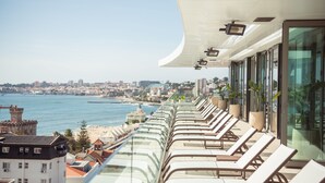 Balcón con sillones de sol con vista a un paisaje urbano costero.