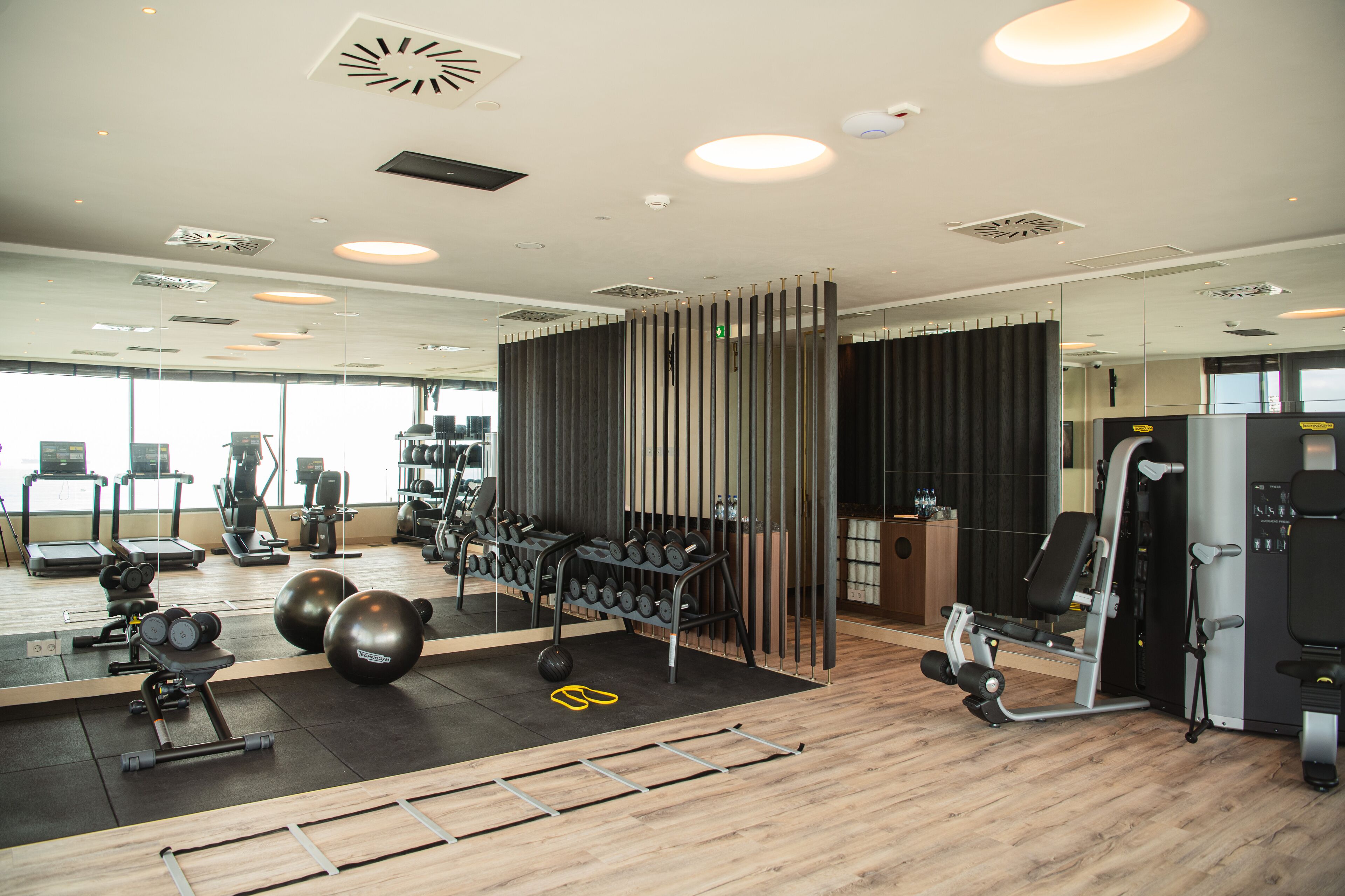 Un gimnasio con equipo de ejercicio, un espejo y suelo de madera.