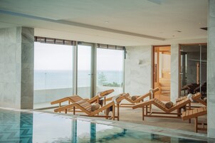 Una piscina cubierta, una piscina al aire libre, sombrillas