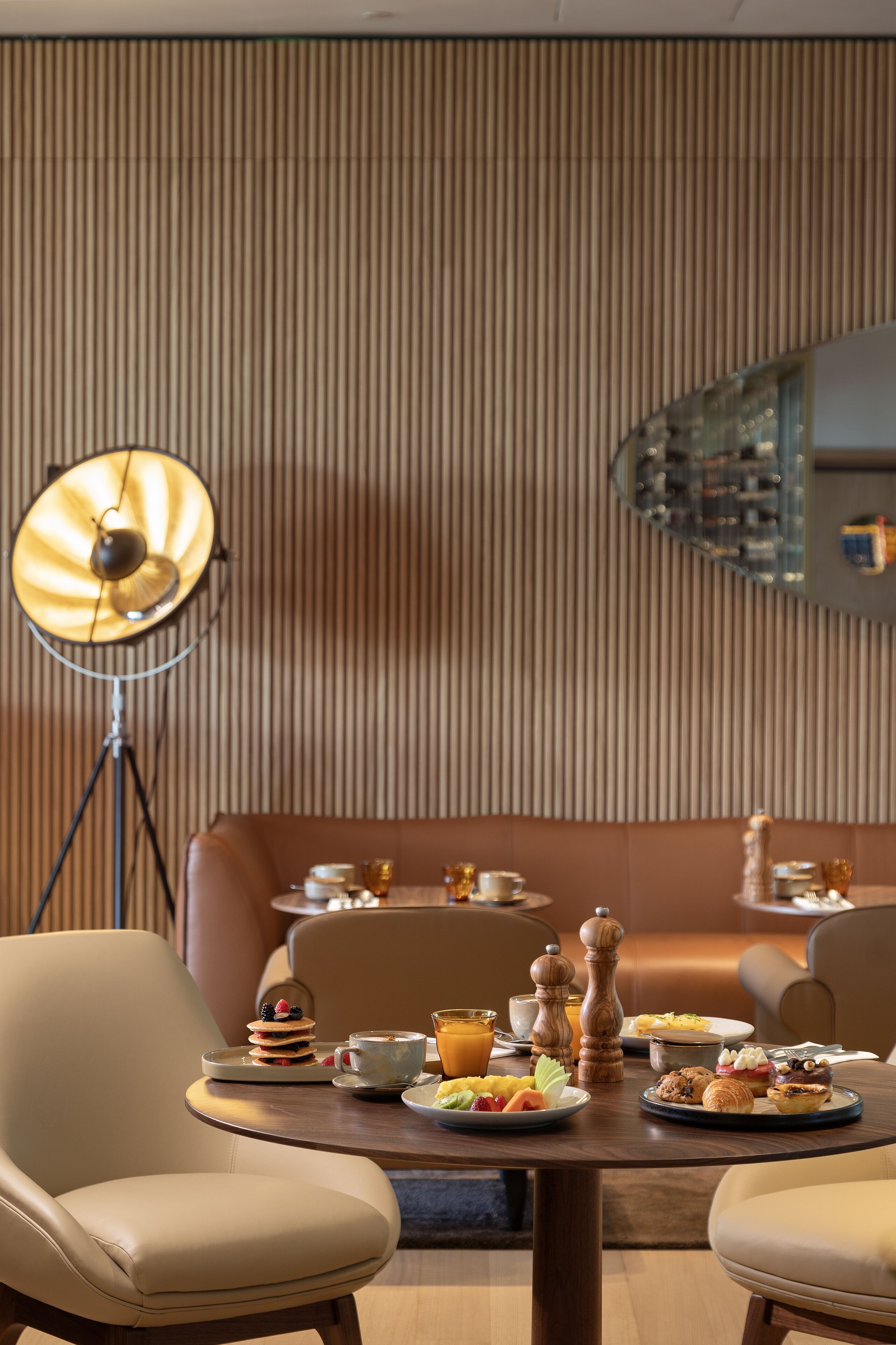 Un coin repas avec une table mise pour le petit-déjeuner, comprenant des assiettes remplies de nourriture, des tasses et une lampe sur pied.