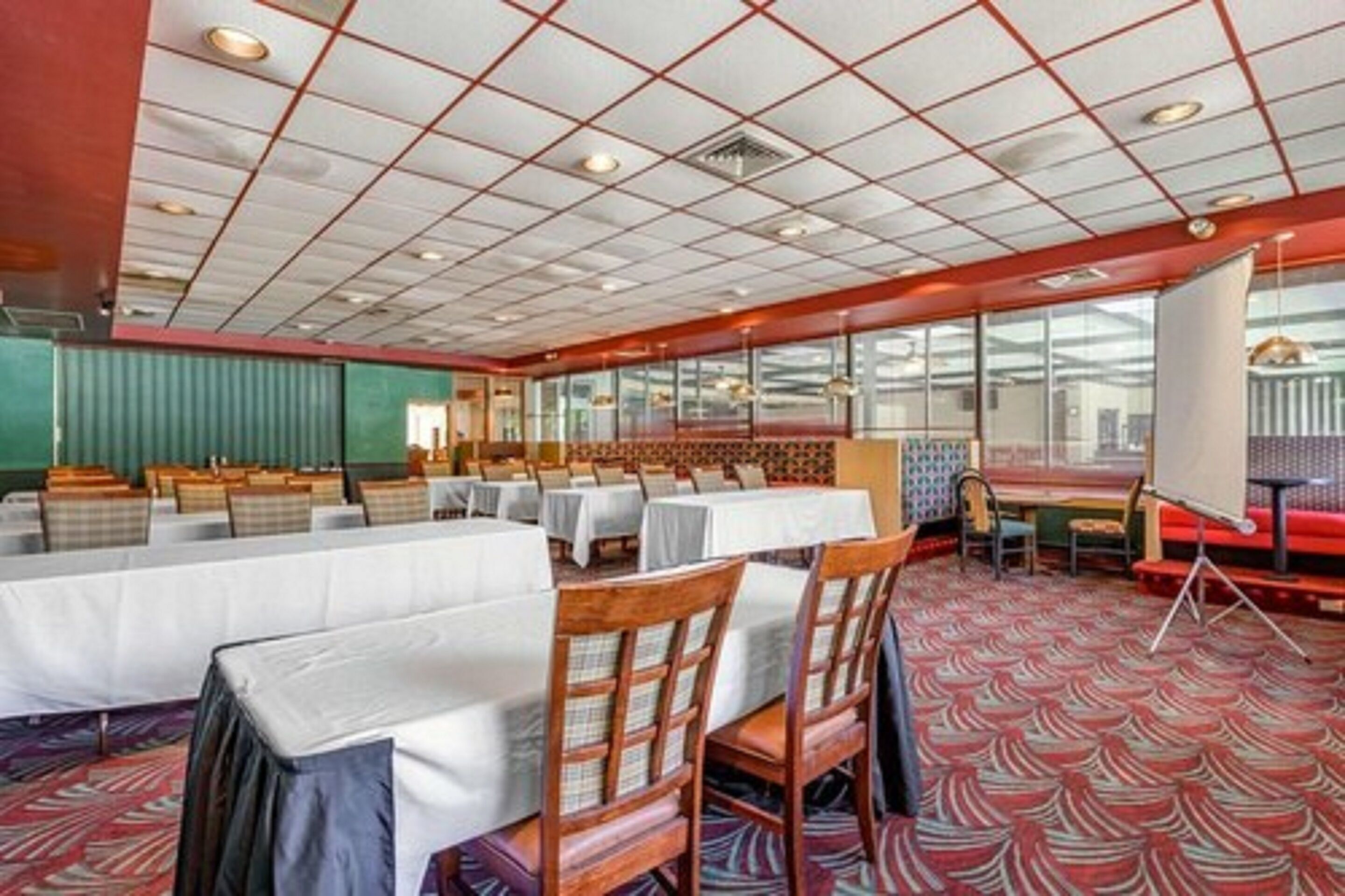 A conference room with tables and chairs, large windows, and a patterned carpet.