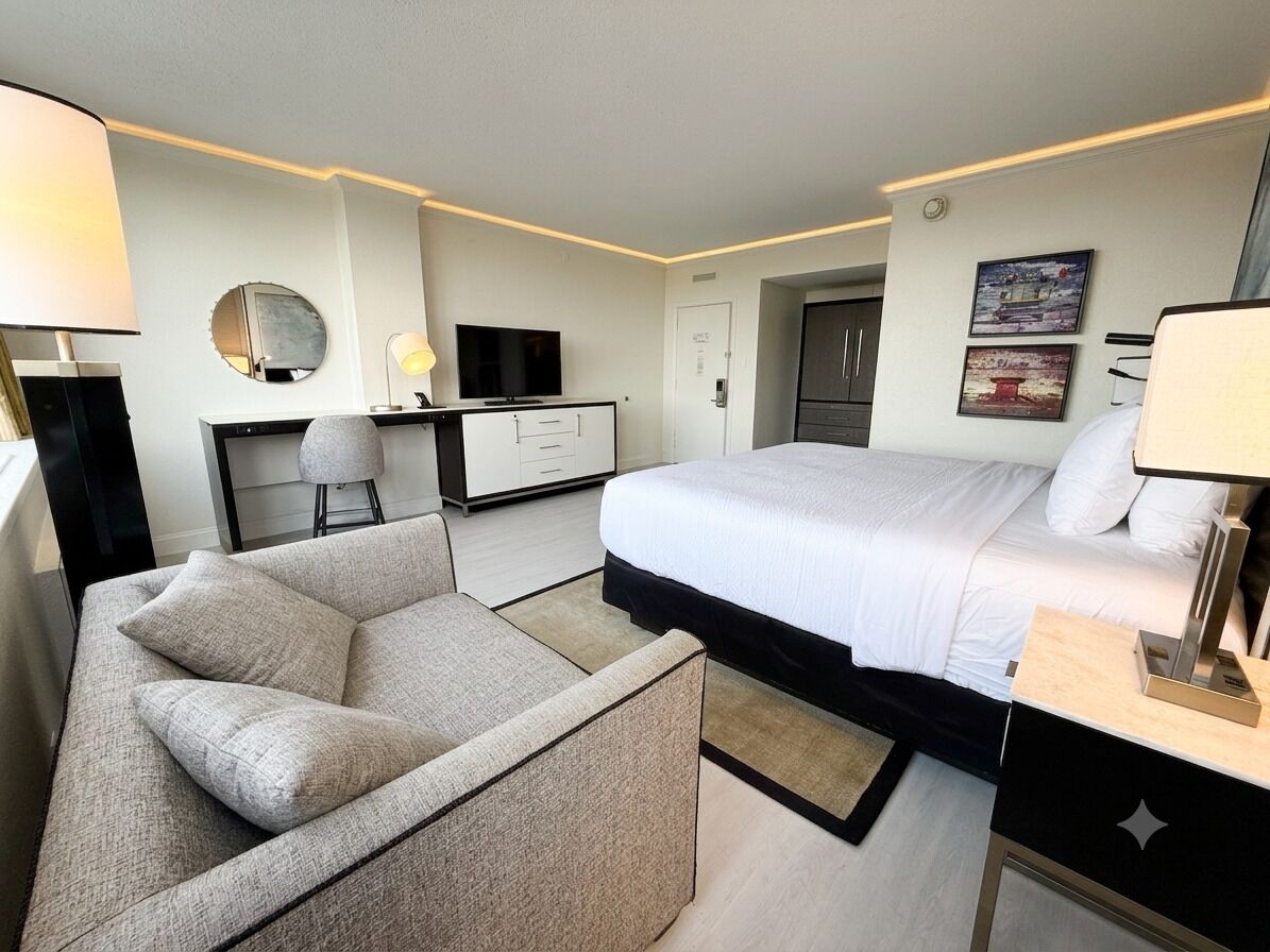 Habitació d'hotel moderna amb llit, escriptori, cadira, televisió i armari.