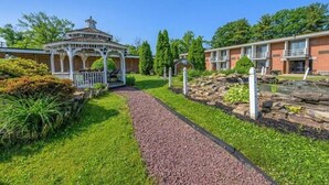 A gazebo with a white railing, a gravel path, and a brick building with a balcony. -  Inn at Lebanon - Hershey & Manheim area (Lebanon)