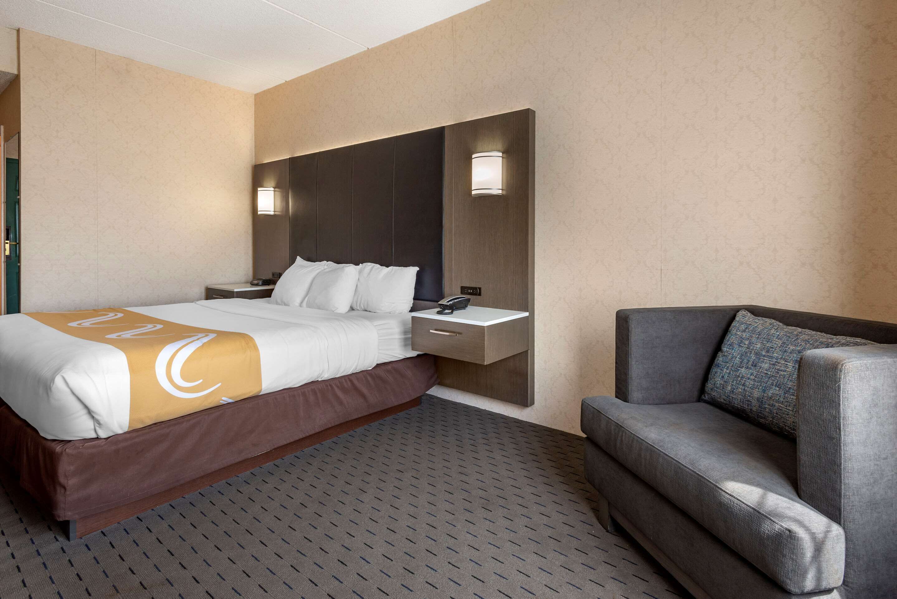 Une chambre d’hôtel avec un lit, une table de chevet et un canapé.