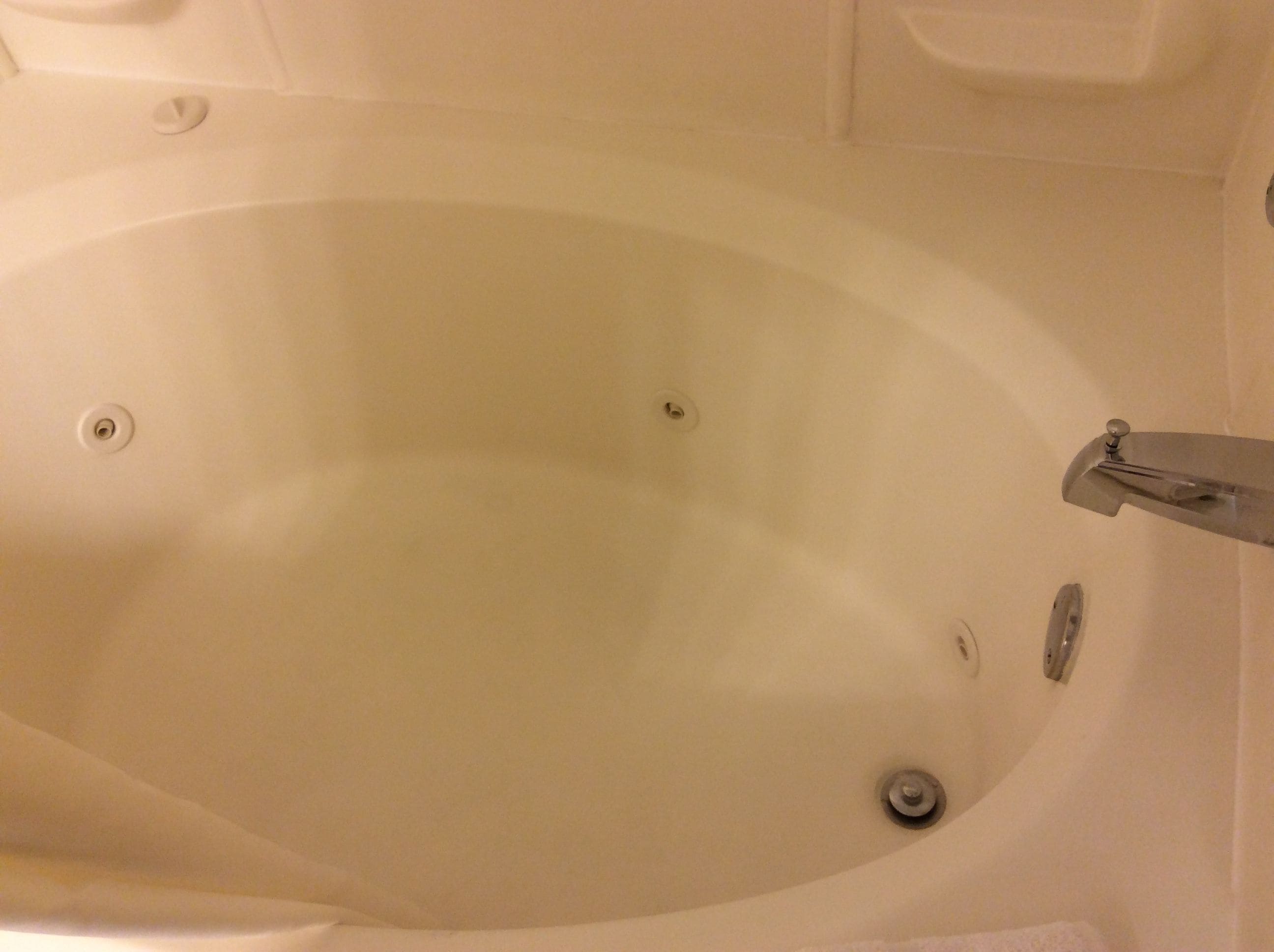 Una bañera blanca con grifo y desagüe.