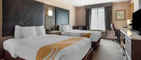 A hotel room with two beds, a desk, a chair, a TV, and a window with curtains.