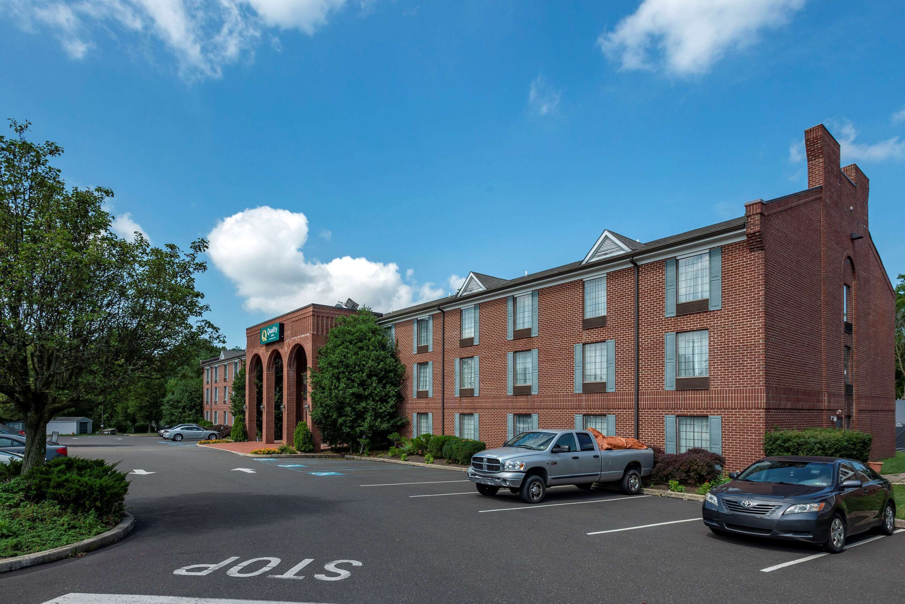 A brick building with a green sign, a parking lot, and a clear blue sky.